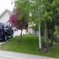 a house with a car parked in a yard with trees