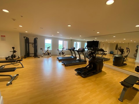 a gym with cardio equipment and weights on a wooden floor