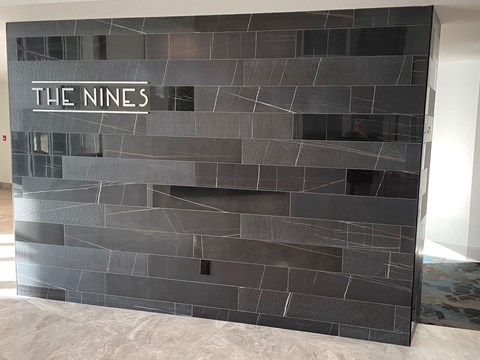 the lobby of the nines has a black tile wall with the names on it