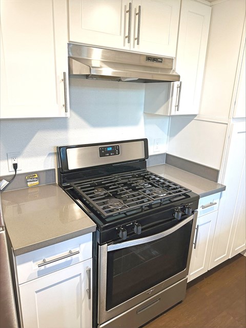 a kitchen with white cabinets and a stove and a microwave