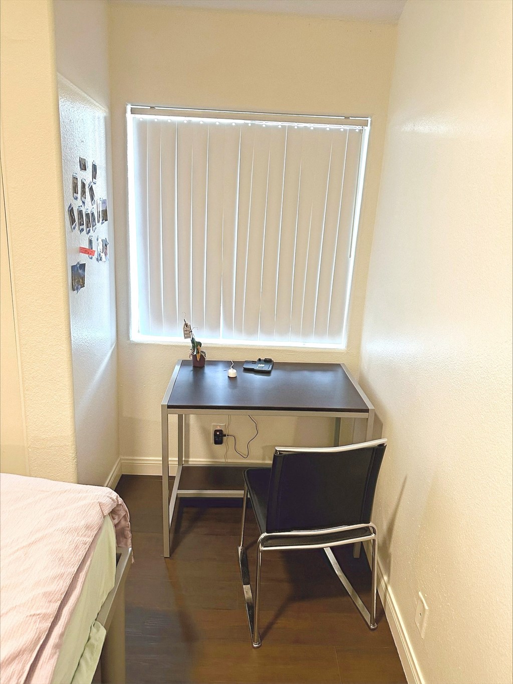 a small bedroom with a desk and a window with white blinds