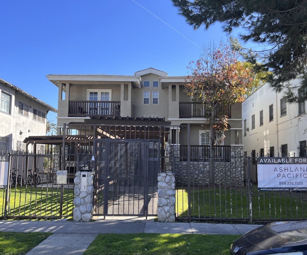 an apartment building with a gate and a sign in front of it