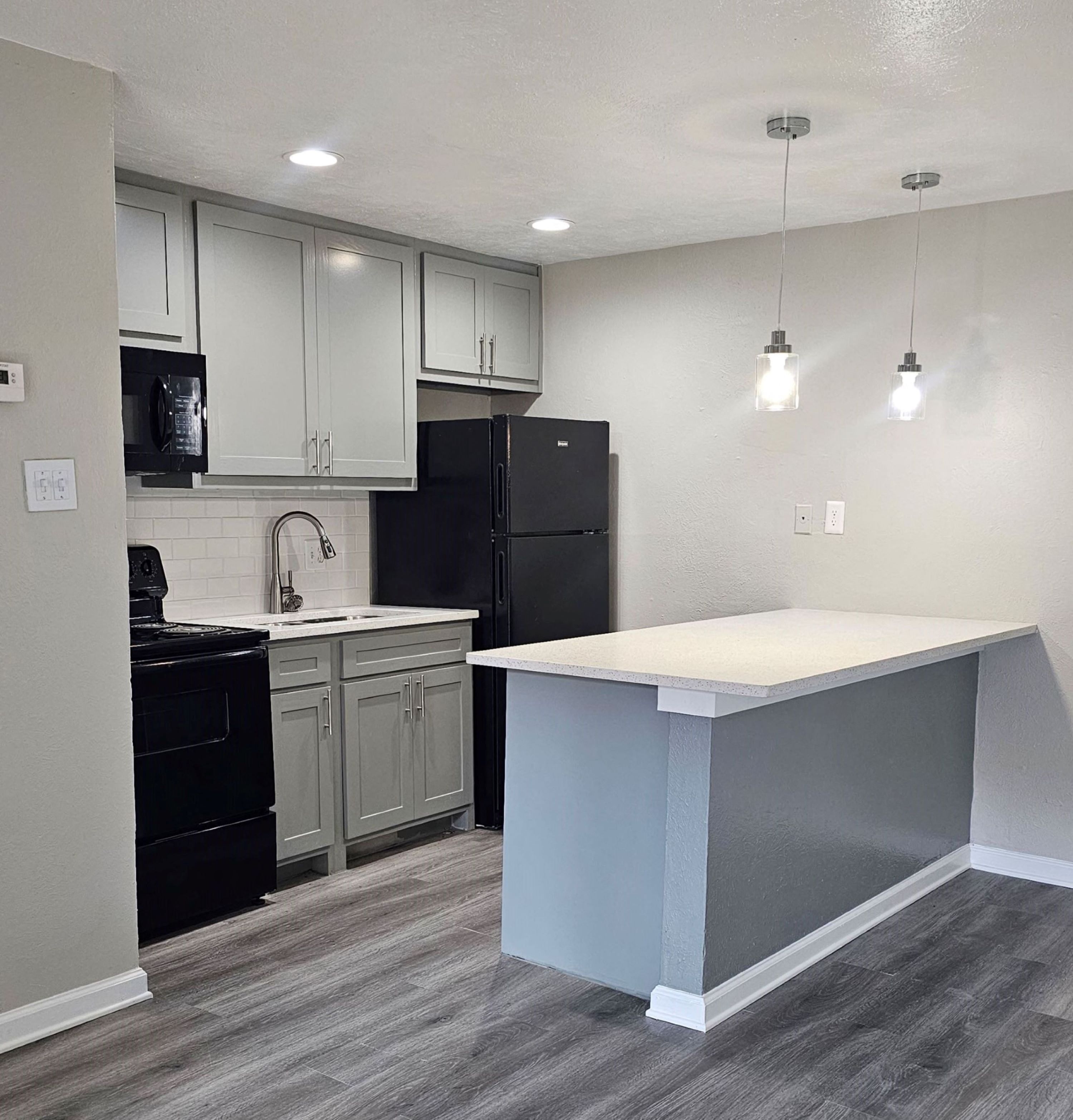 A kitchen with a black refrigerator and a white island.