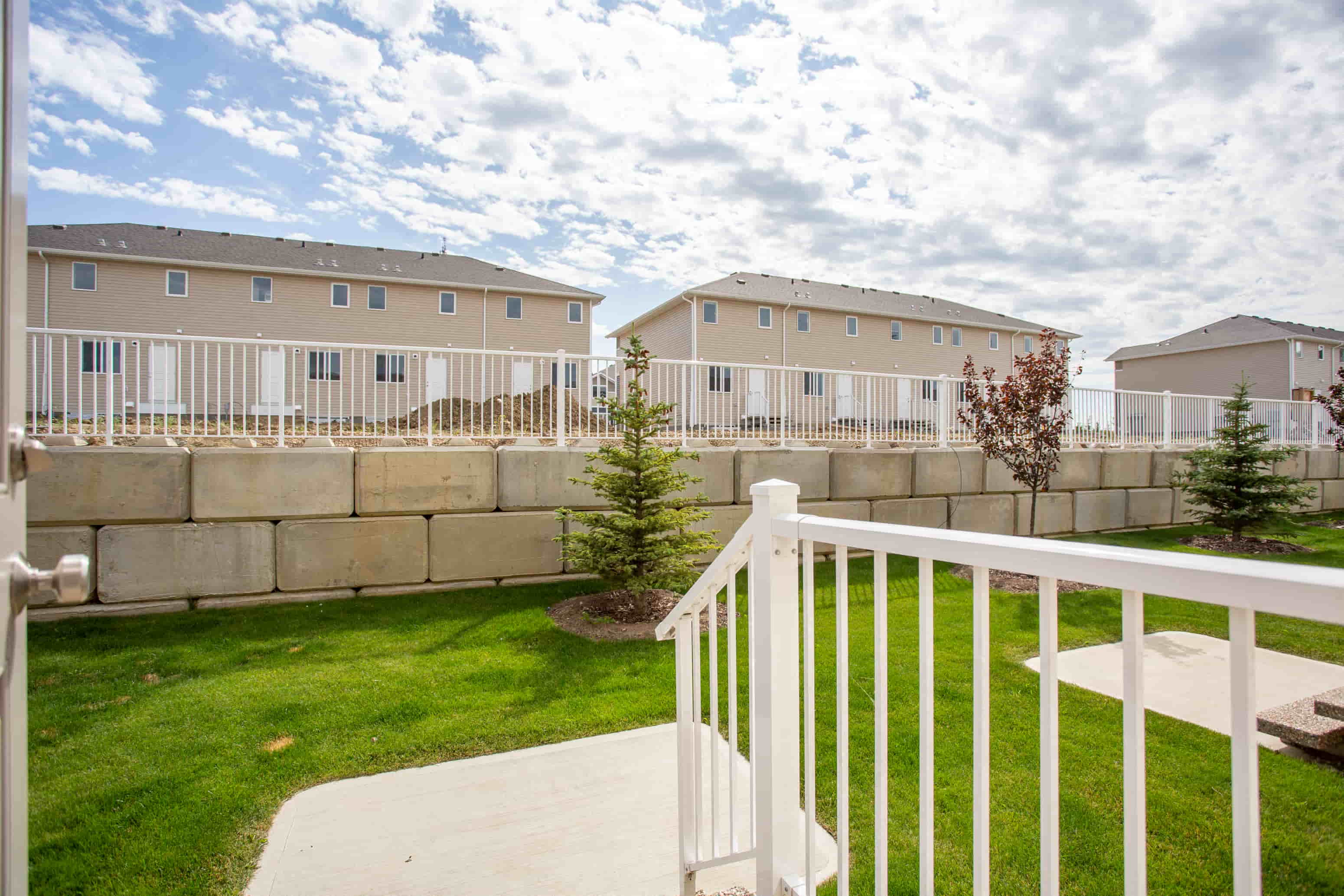 A white fence surrounds a grassy area with a building in the background.
