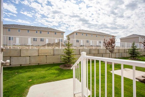 A white fence surrounds a grassy area with a building in the background.