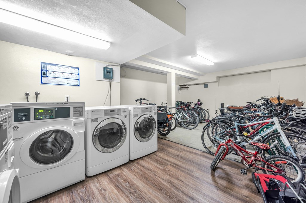 A laundry room with washers and dryers and bicycles in the background.