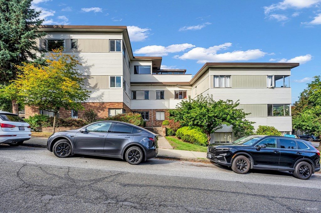 Two cars parked in front of a two-story apartment building.