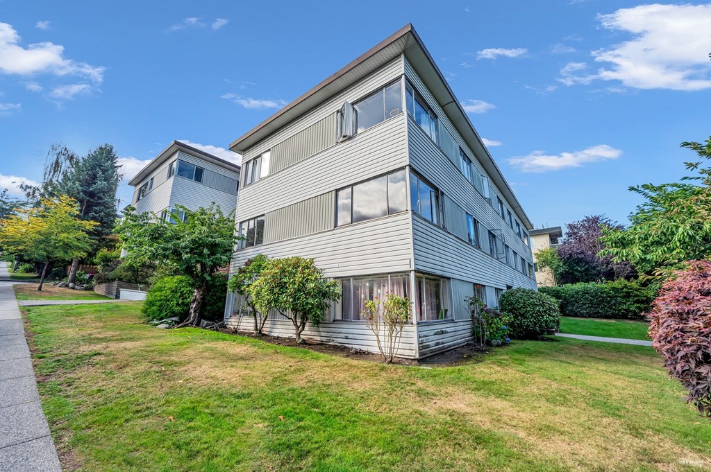 A modern house with a grey facade and a well-maintained lawn.