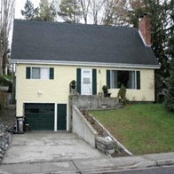 A small house with a green door and a grey garage door.
