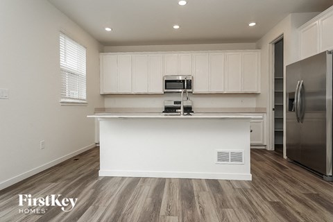 A kitchen with white cabinets and a wooden floor.