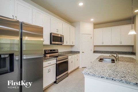 A kitchen with a granite counter top and stainless steel appliances.