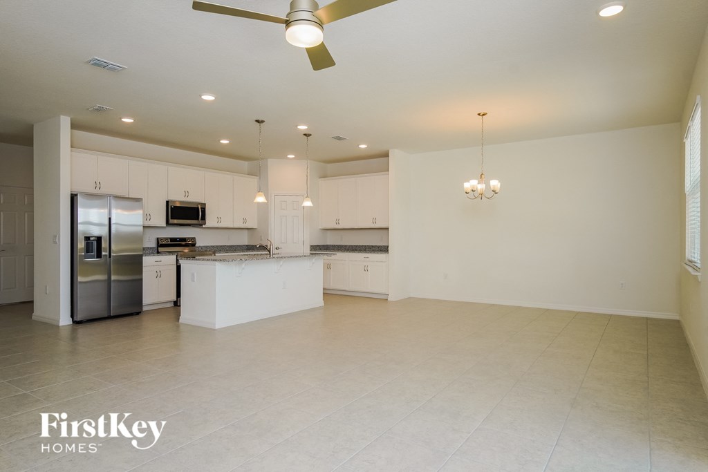 A spacious kitchen with a fan and a chandelier.