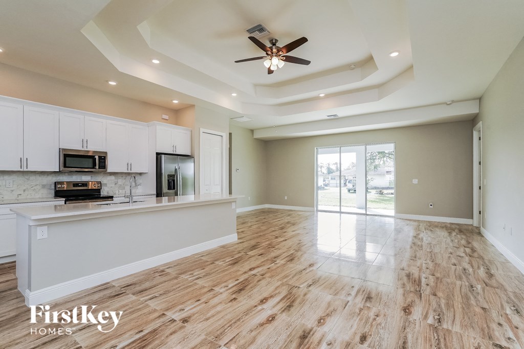 A spacious kitchen and living room with wooden floors and a ceiling fan.