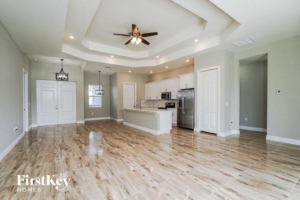 A spacious kitchen with wooden floors and a ceiling fan.