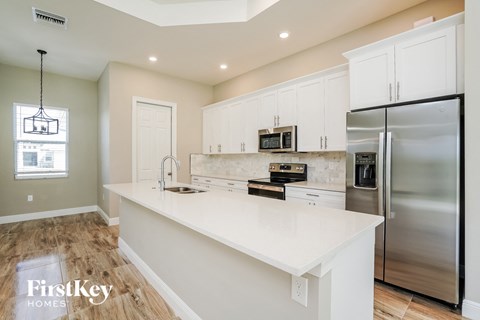 A kitchen with a stainless steel refrigerator and white countertops.