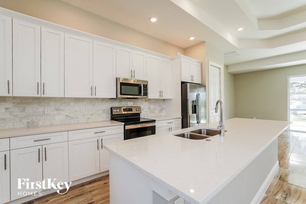 A kitchen with white cabinets and a white countertop.