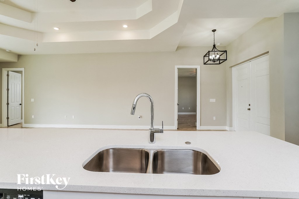 A modern kitchen with a stainless steel sink and a hanging light fixture.
