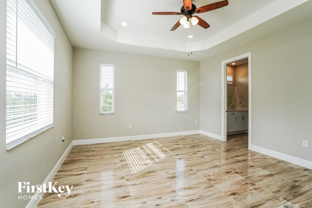 A room with a ceiling fan and wooden flooring.