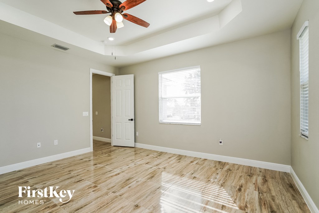 A room with a ceiling fan and wooden flooring.