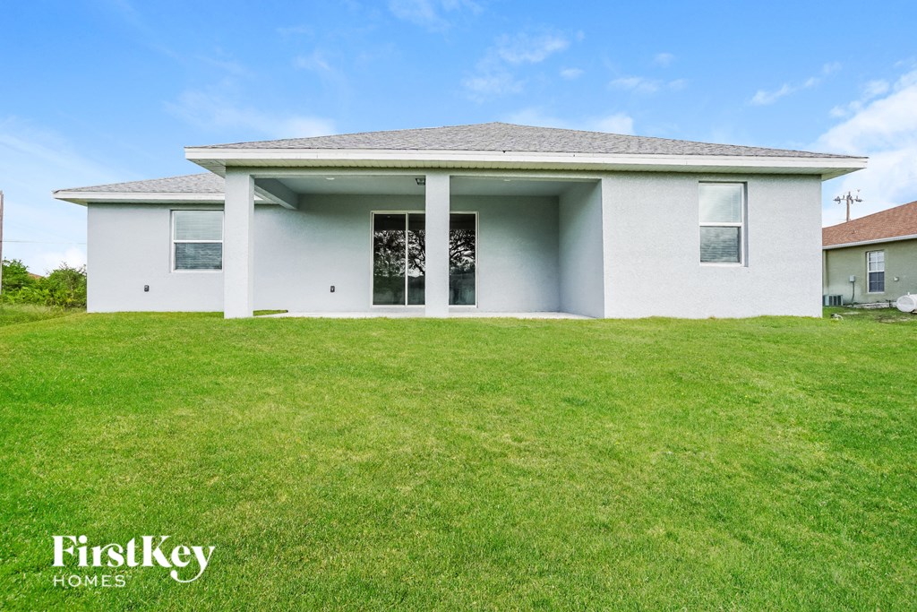 A white house with a grey roof and a green lawn in front.