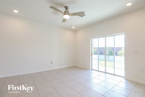 A spacious room with a ceiling fan and sliding glass doors leading to a patio.