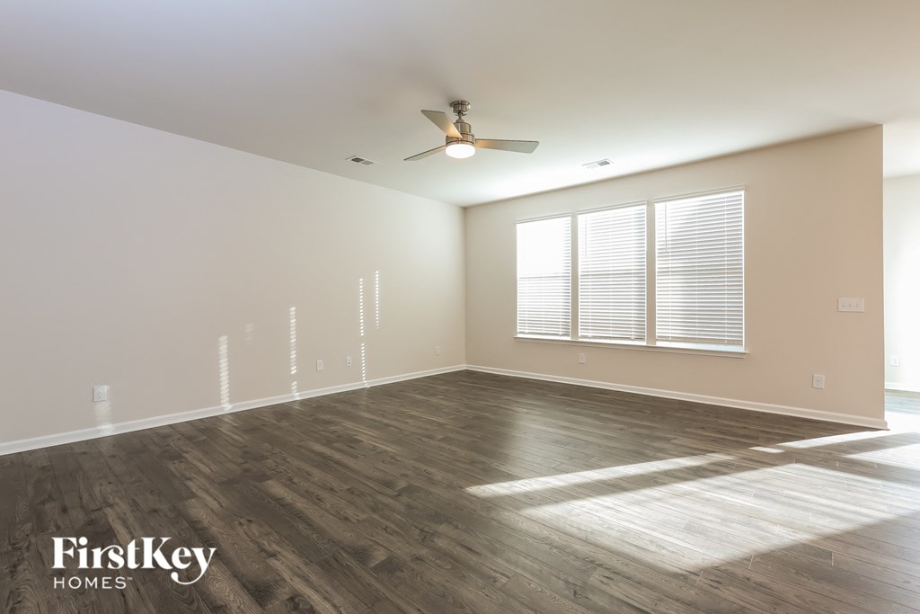 A spacious room with wooden flooring and a ceiling fan.