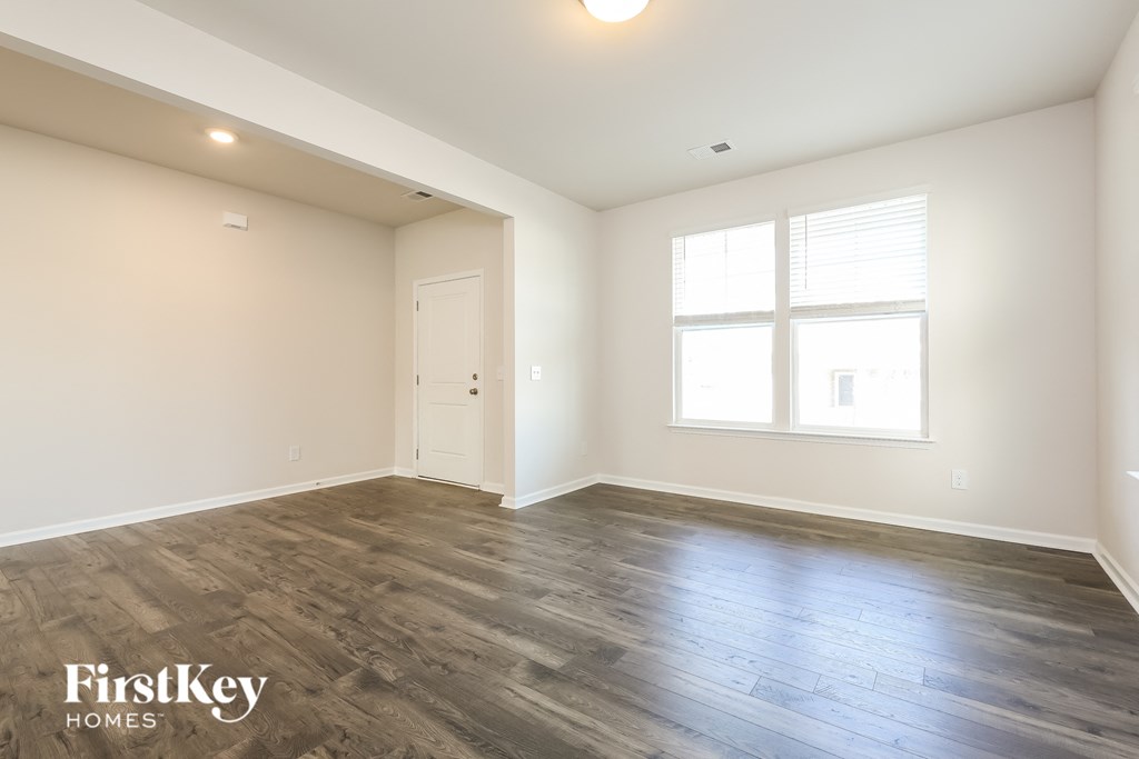 A spacious room with wooden flooring and a window.