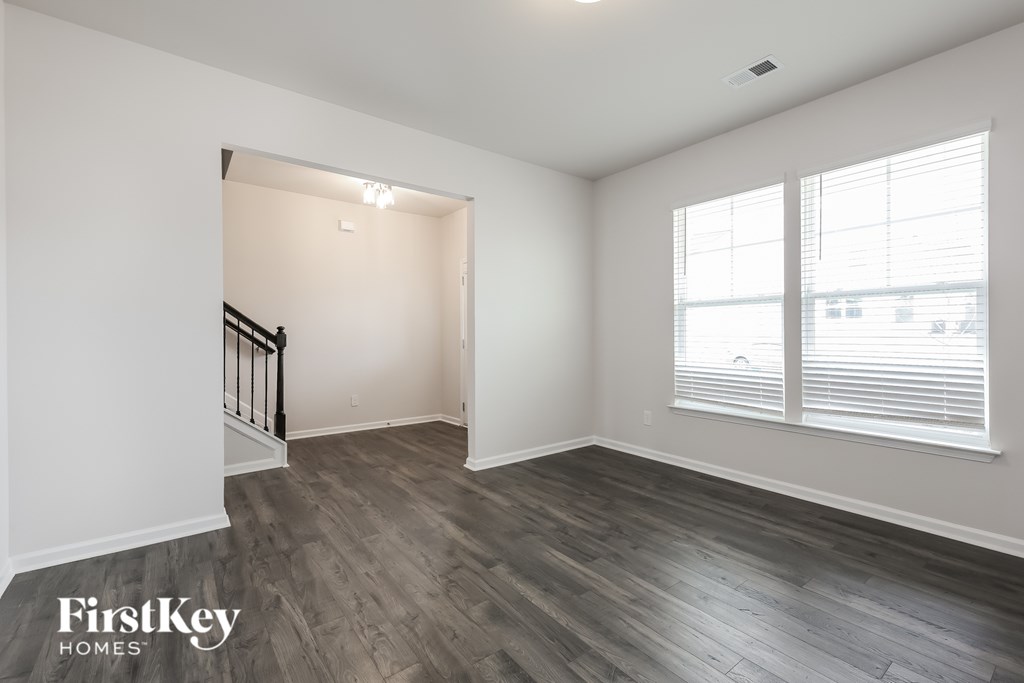 A room with wooden flooring and a staircase leading to another room.