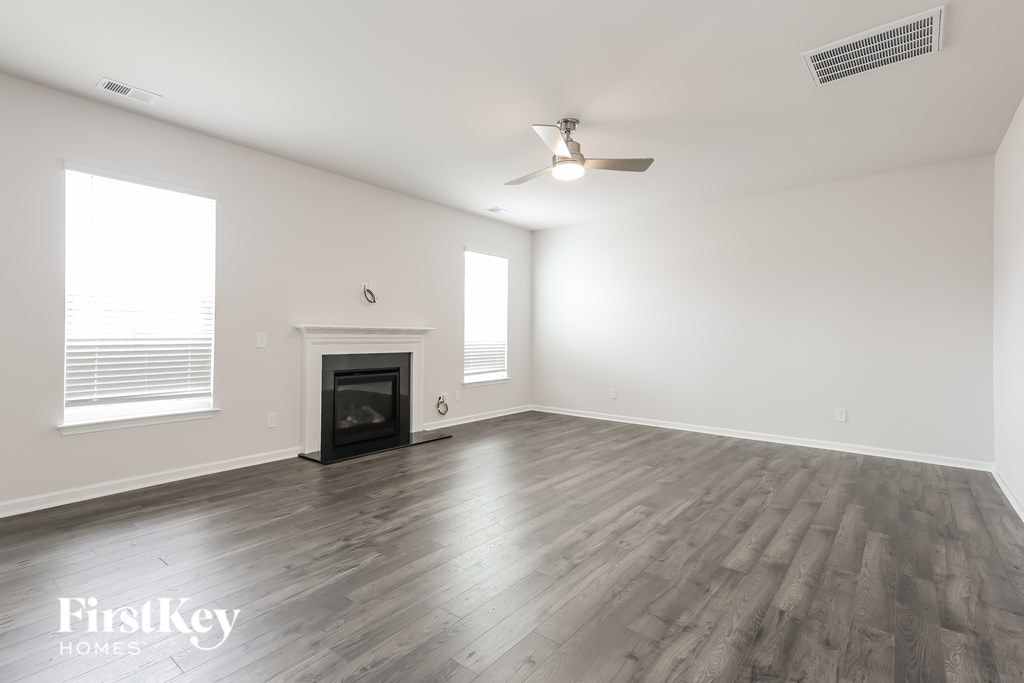 A spacious room with a fireplace and a ceiling fan.