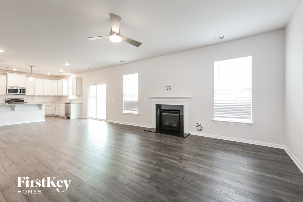 A spacious living room with a fireplace and a fan on the ceiling.