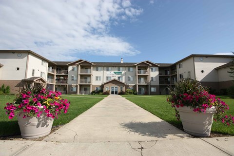 A building with a walkway in front and two large pots of flowers on the sides.