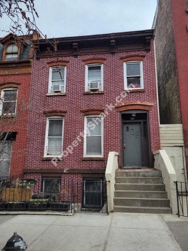 a red brick house with a gray door and stairs