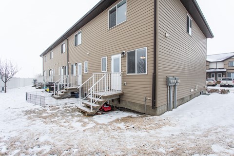 A house with a snow-covered ground in front of it.