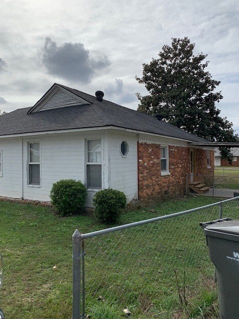 A white house with a grey roof and a grey fence in front of it.