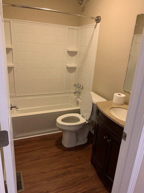 A white toilet in a bathroom with a wooden floor.