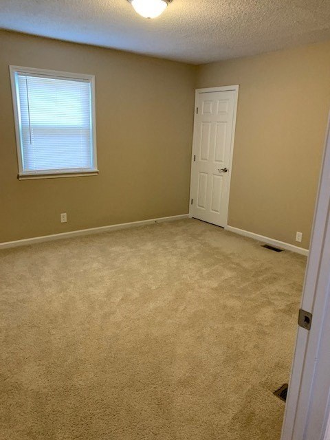 A room with a carpeted floor, a door, and a window with blinds.