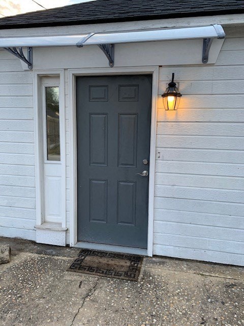 A white house with a grey door and a light on.