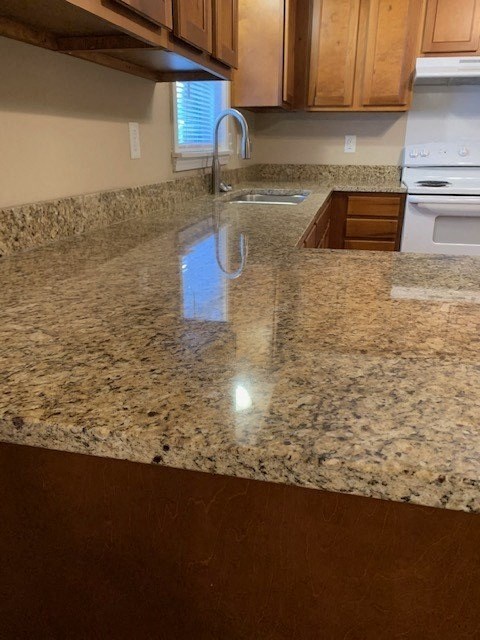A kitchen counter with a granite top and a stainless steel sink.