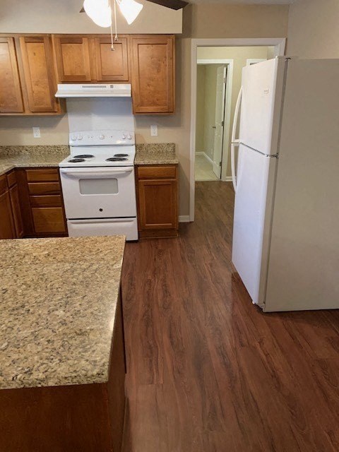 A kitchen with a white stove and a white refrigerator.