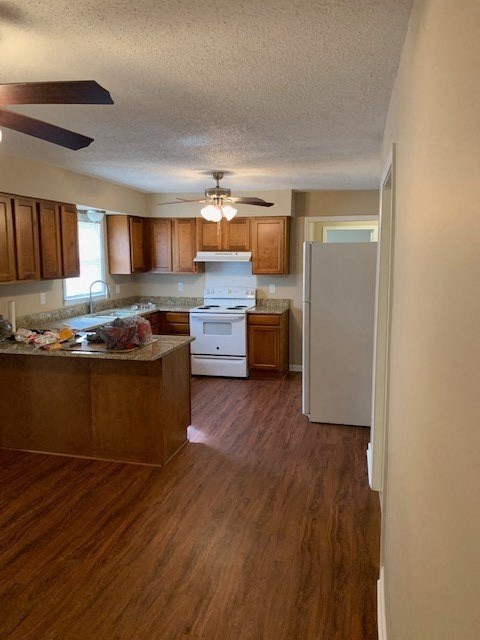 A kitchen with wooden floors and white appliances.
