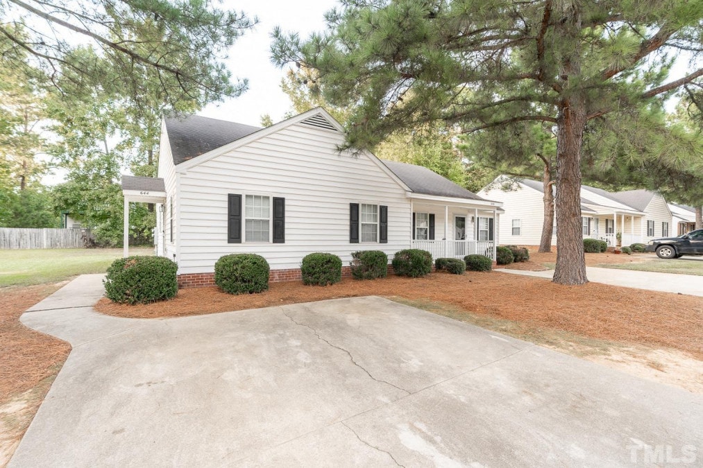 A white house with a black roof and a driveway in front.