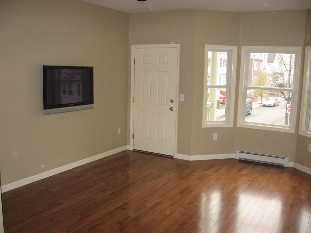 an empty living room with wood floors and a tv