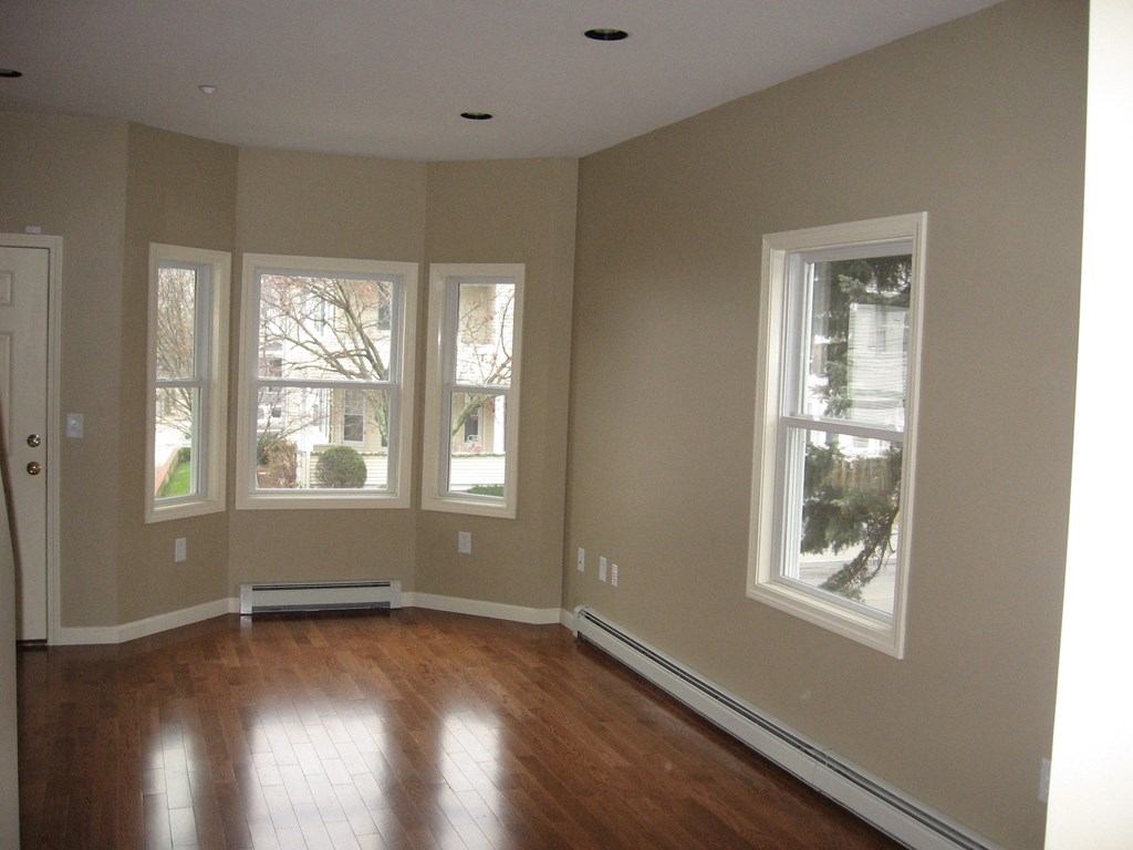 an empty living room with a hard wood floor and large windows
