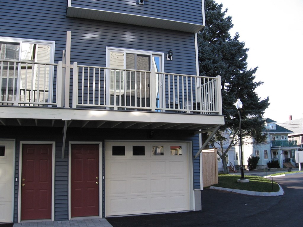 a blue house with a balcony and a white garage door