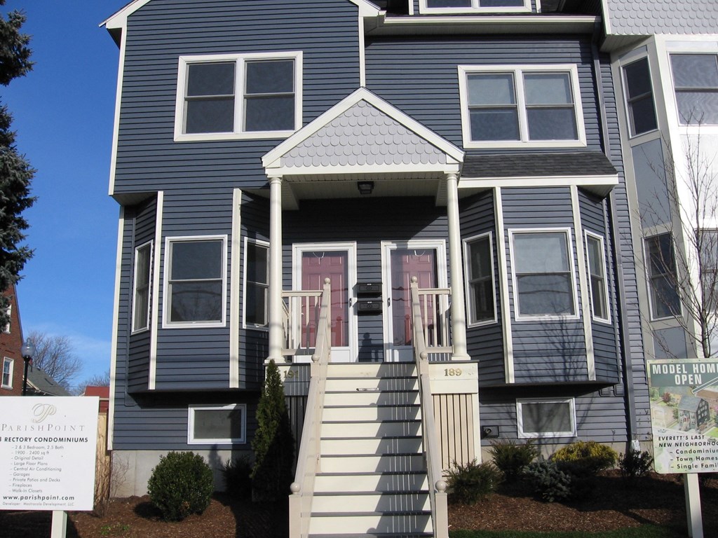 the front of a blue house with stairs and a red door