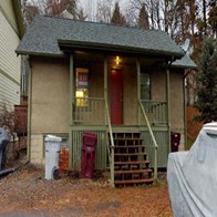A small house with a red door and a green staircase.