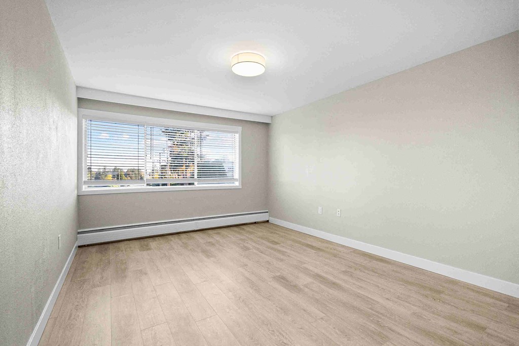 an empty living room with a window and wood floors