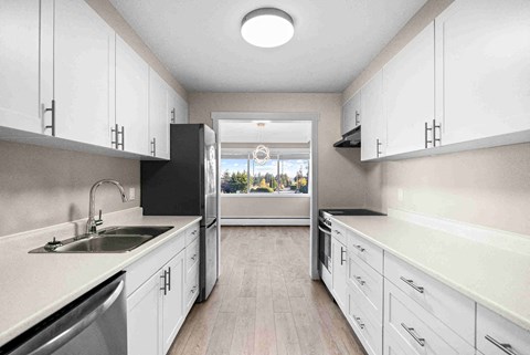 a kitchen with white cabinets and a sink and a window