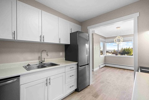 a kitchen with white cabinets and a stainless steel refrigerator