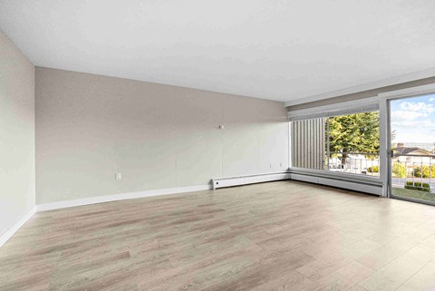 an empty living room with a large window and wood floors
